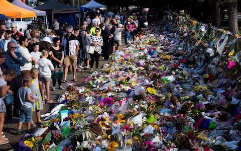 Floral tributes to those who were gunned down at the two mosques are seen against a wall bordering the Botanical Garden in Christchurch - Credit: &nbsp;MARTY MELVILLE/AFP