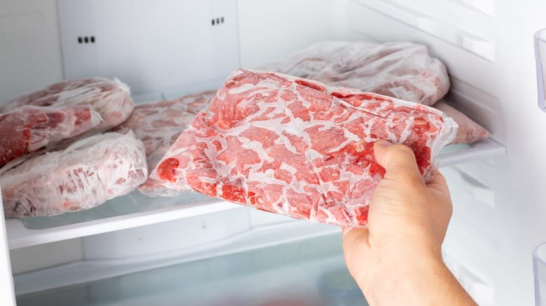 Hand removing meat from freezer