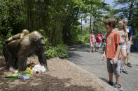 <p>Visitors pass a gorilla statue where flowers have been placed outside the Gorilla World exhibit at the Cincinnati Zoo & Botanical Garden. <em>(AP Photo/John Minchillo)</em> </p>