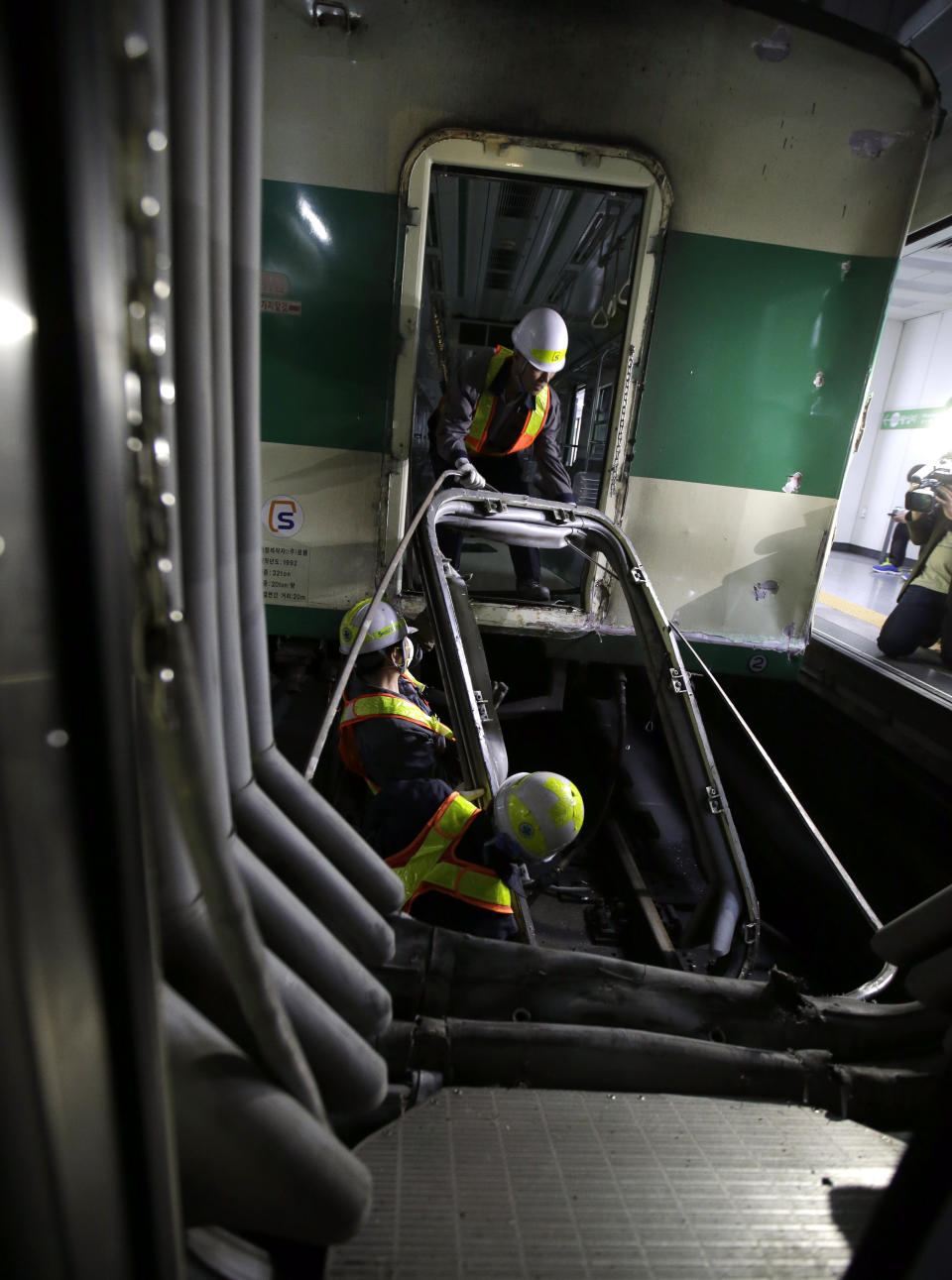 South Korea's subway workers try to repair the train at Sangwangshipri station after a collision in Seoul, South Korea, Friday, May 2, 2014. The subway train hit another train stopped at the station in South Korea's capital on Friday, causing minor injuries for scores of people, a city official said. (AP Photo/Lee Jin-man)