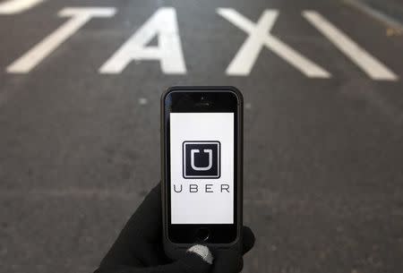 The logo of car-sharing service app Uber on a smartphone over a reserved lane for taxis in a street is seen in this photo illustration taken in Madrid on December 10, 2014. REUTERS/Sergio Perez