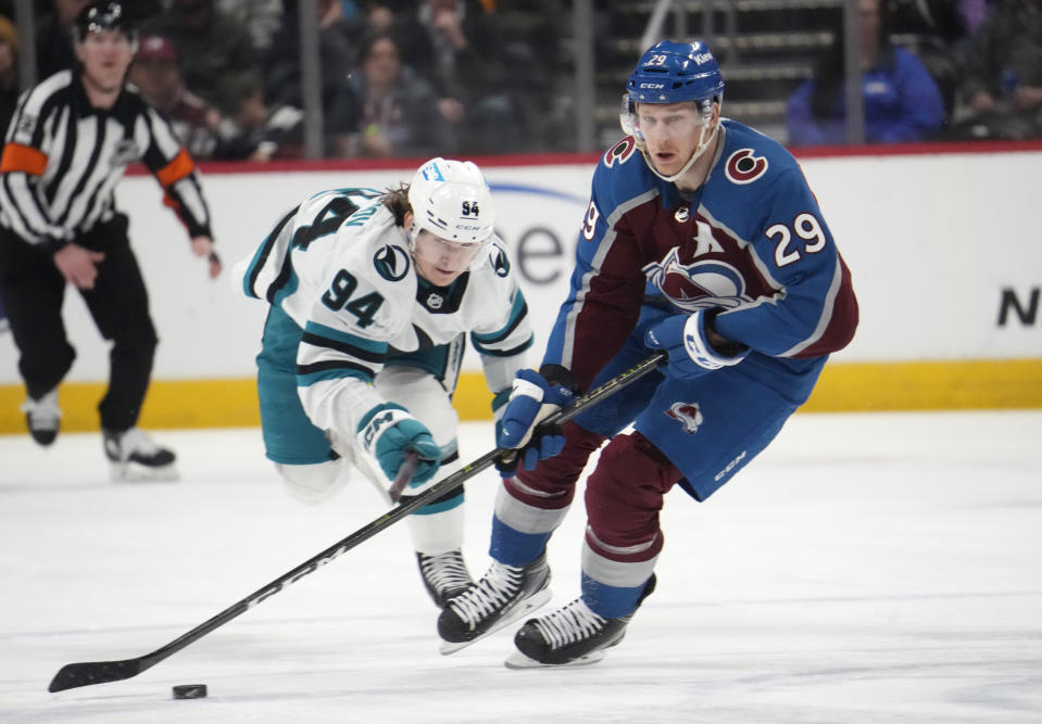 Colorado Avalanche center Nathan MacKinnon, front, drives down the ice with the puck as San Jose Sharks left wing Alexander Barabanov pursues in the first period of an NHL hockey game Tuesday, March 7, 2023, in Denver. (AP Photo/David Zalubowski)