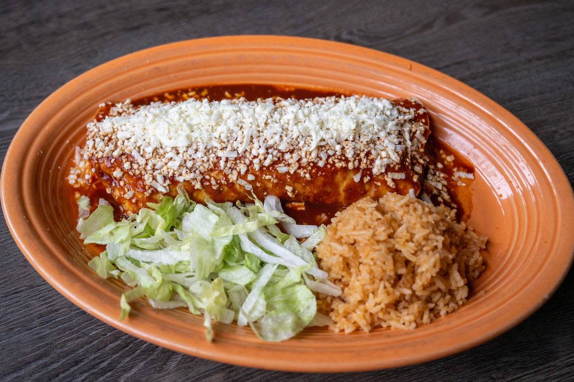 The enchilada burrito, featuring pork, chicken, or ground beef options, is wrapped in a flour tortilla with refried beans, topped with house-made enchilada sauce and queso fresco and served with a side of rice and lettuce at Rudy’s Tenampa Taqueria. Emily Curiel/ecuriel@kcstar.com