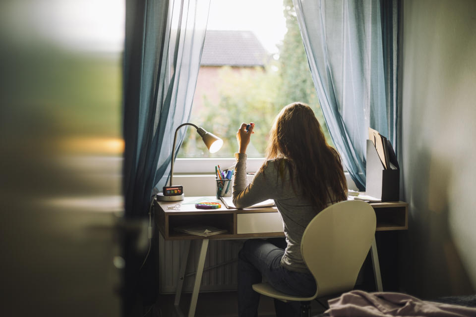 Person sitting at a desk by a window, working or studying, in a serene setting