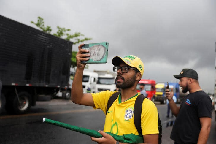 Un hombre utiliza su teléfono el martes mientras los partidarios del presidente de Brasil Jair Bolsonaro, principalmente camioneros, bloquean una carretera durante una protesta por la derrota de Bolsonaro en la segunda vuelta de las elecciones presidenciales, en Itaborai, en el estado de Río de Janeiro