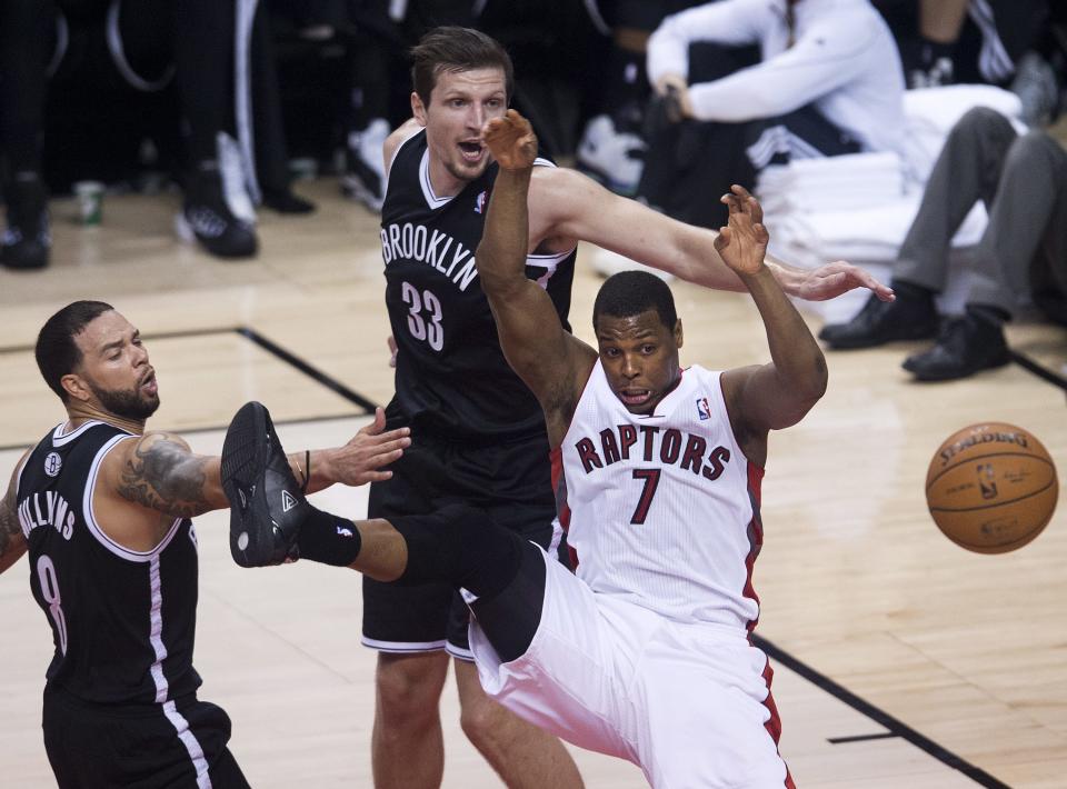 Toronto Raptors guard Kyle Lowry (7) loses control of the ball while driving toward the net past Brooklyn Nets' Mirza Teletovic, center, and Deron Williams, left, during the second half of Game 5 of the opening-round NBA basketball playoff series in Toronto, Wednesday, April 30, 2014. (AP Photo/The Canadian Press, Nathan Denette)