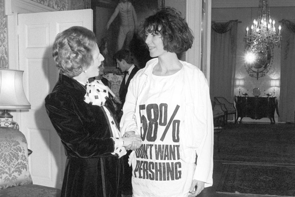 Prime Minister Margaret Thatcher greets fashion designer Katharine Hamnett, wearing a T-shirt with a nuclear missile protest message, at 10 Downing Street, where she hosted a reception for British Fashion Week designers. (Photo: PA Images via Getty Images)