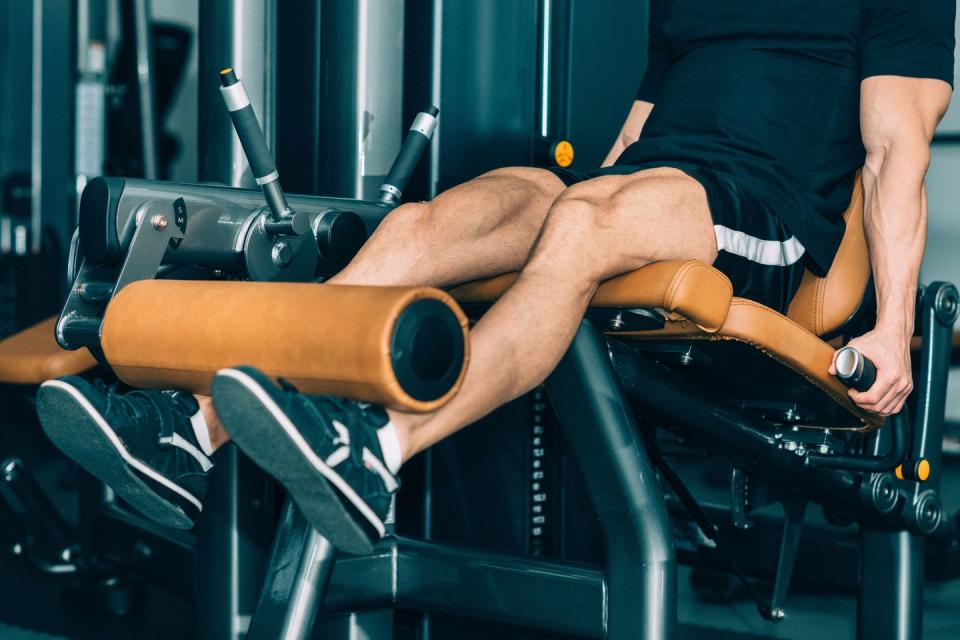 a man using a leg extension machine in the gym