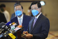 John Lee, right, former No. 2 official in Hong Kong, and the only candidate for the city's top job, takes note during a press conference after announcing his manifesto for the 2022 chief executive electoral campaign in Hong Kong, Friday, April 29, 2022. Lee formally registered his candidacy for chief executive earlier this month after securing 786 nominations to enter the race. (AP Photo/Kin Cheung)