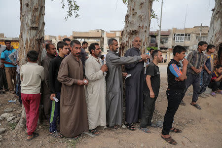 Displaced Iraqi men wait to receive humanitarian aid as the battle between the Iraqi Counter Terrorism Service and Islamic State militants continues nearby, in western Mosul, Iraq, April 23, 2017. REUTERS/Marko Djurica