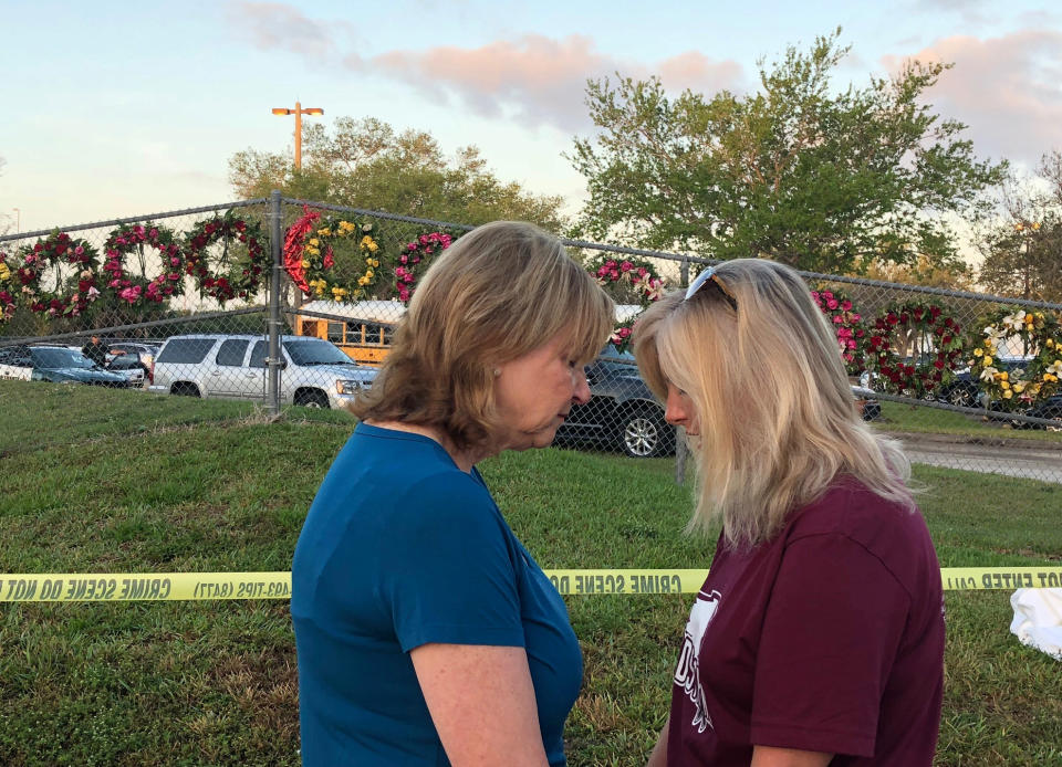 <p>Beverly Turner and Michele Brown huddle to pray in front of a chain-link fence decorated with wreaths as students and faculty arrive at Marjory Stoneman Douglas High School for the first time since the mass shooting in Parkland, Florida, U.S., February 28, 2018. REUTERS/Bernie Woodall </p>