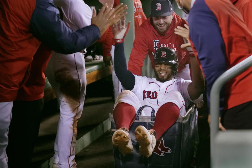 Boston Red Sox's Xander Bogaerts high-fives teammates while being pushed in a laundry cart through the dugout after his two-run home run against the Detroit Tigers during the second inning of a baseball game at Fenway Park, Tuesday, May 4, 2021, in Boston. (AP Photo/Charles Krupa)