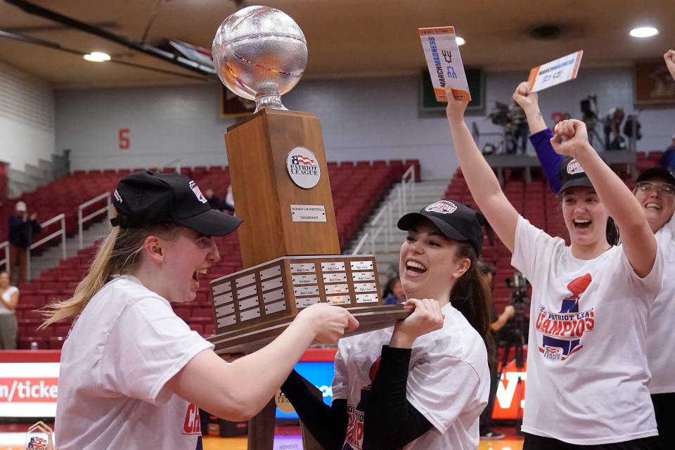 Holy Cross guard Bronagh Power-Cassidy, left, guard Addisyn Cross, center, and forward Lindsay Berger, right, celebrate with the Patriot League championship trophy.