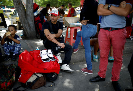 Dario Leal, 30, (C), a Venezuelan baker who entered Colombia by crossing the Tachira river, sits on the sidewalk next to a pair of shoes being sold by a friend, on his second day in Villa del Rosario, Colombia August 25, 2018. REUTERS/Carlos Garcia Rawlins