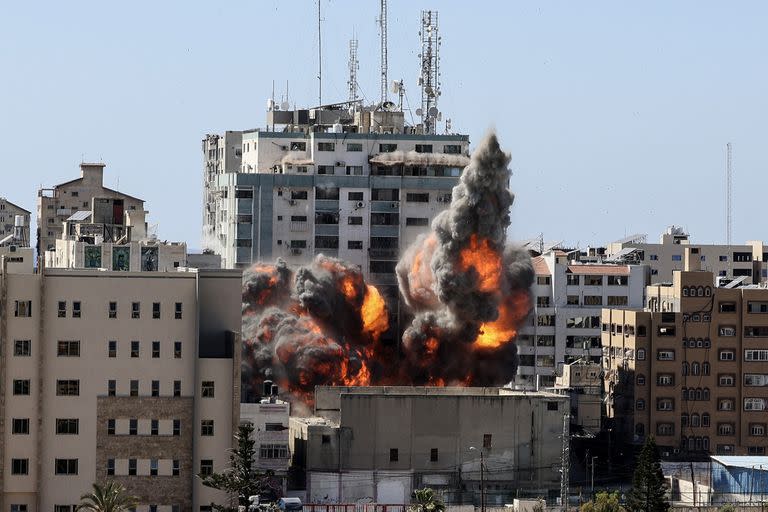 Una bola de fuego estalla desde la Torre Jala cuando es destruida en un ataque aéreo israelí en la ciudad de Gaza controlada por el movimiento palestino Hamas, el 15 de mayo de 2021. - Los ataques aéreos israelíes golpearon la Franja de Gaza, matando a 10 miembros de una familia extendida y demoliendo un edificio de medios clave, mientras militantes palestinos lanzaron cohetes a cambio en medio de la violencia en Cisjordania. La fuerza aérea de Israel apuntó a la Torre Jala de 13 pisos que alberga la televisión Al-Jazeera con sede en Qatar y la agencia de noticias Associated Press.