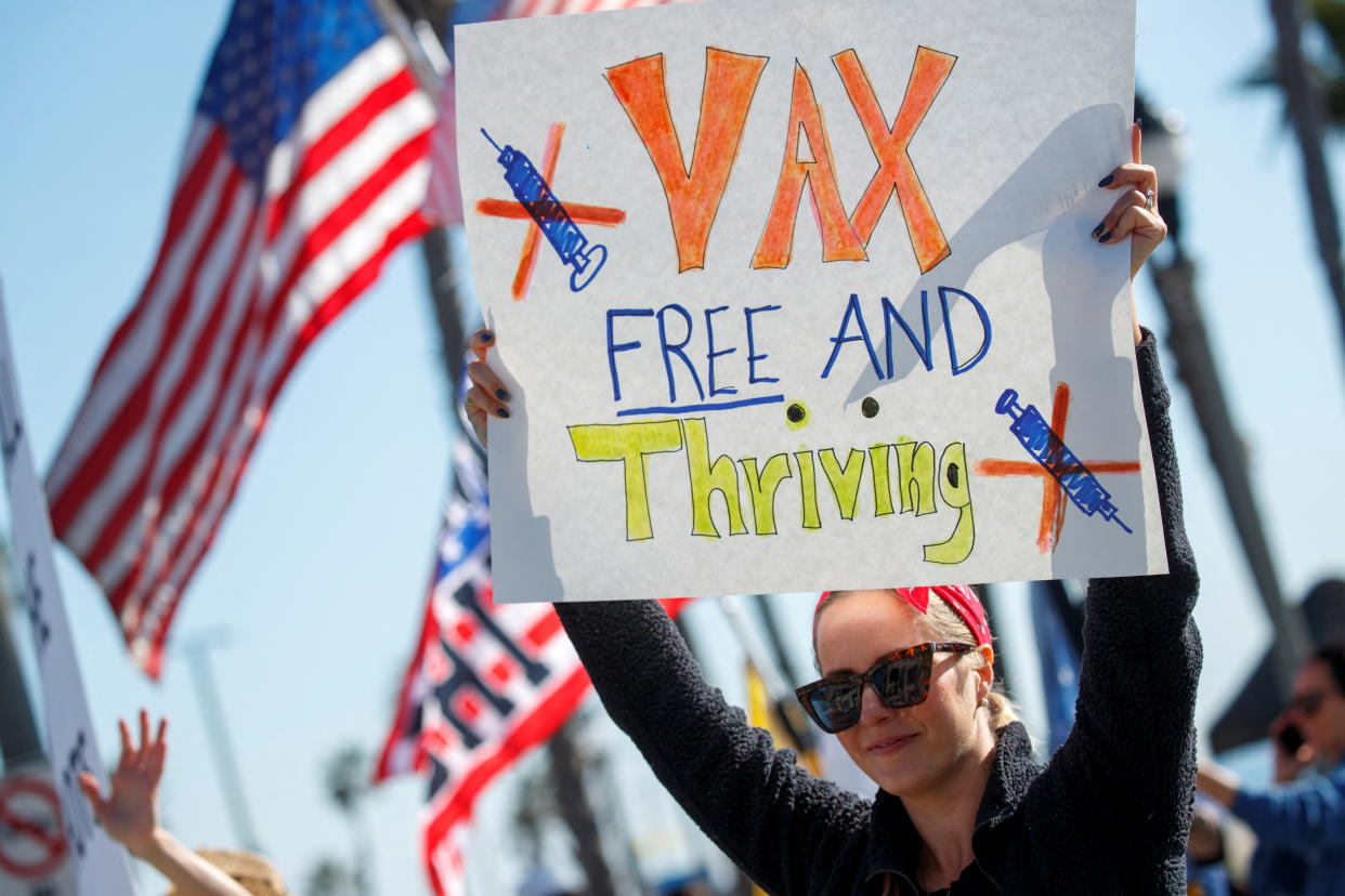 A woman holds a sign as various activist groups hold a rally at the Huntington Beach Pier to speak out against COVID-19 vaccine mandates for school children and workers that may be mandated by State legislature in the coming year, amid the coronavirus disease (COVID-19) pandemic, in Huntington Beach, California, U.S., January 3, 2022. REUTERS/Mike Blake