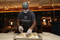 Sharon Holm, a volunteer from Food Rescue US, prepares cold cuts for sandwiches at Marcus Samuelsson's Red Rooster Restaurant during the new coronavirus pandemic, Monday, April 6, 2020, in the Overtown neighborhood of Miami. Samuelsson has partnered with chef Jose Andres' World Central Kitchen to distribute meals to those in need. (AP Photo/Lynne Sladky)