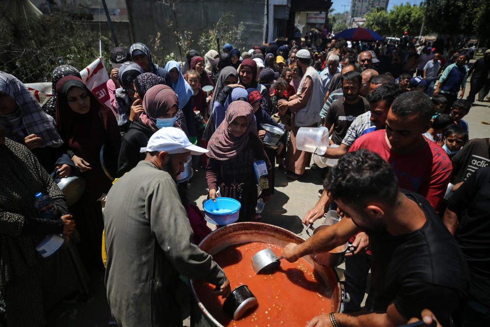加薩地區流離失所的巴勒斯坦人13日在公共廚房領取食物。（Photo by Majdi Fathi/NurPhoto/Getty Images）