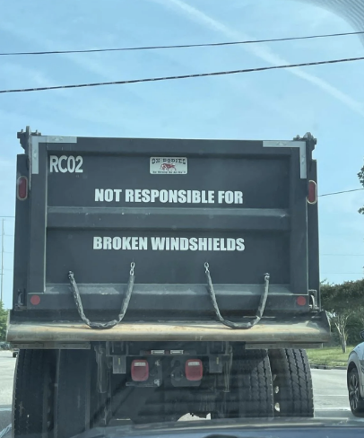 Back of a truck with a sign reading "NOT RESPONSIBLE FOR BROKEN WINDSHIELDS."