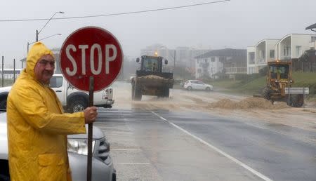 Loaders move tons of sand pushed by strong winds and rain onto a coastal road in Sydney's beachside suburb of Cronulla, April 21, 2015. REUTERS/Jason Reed