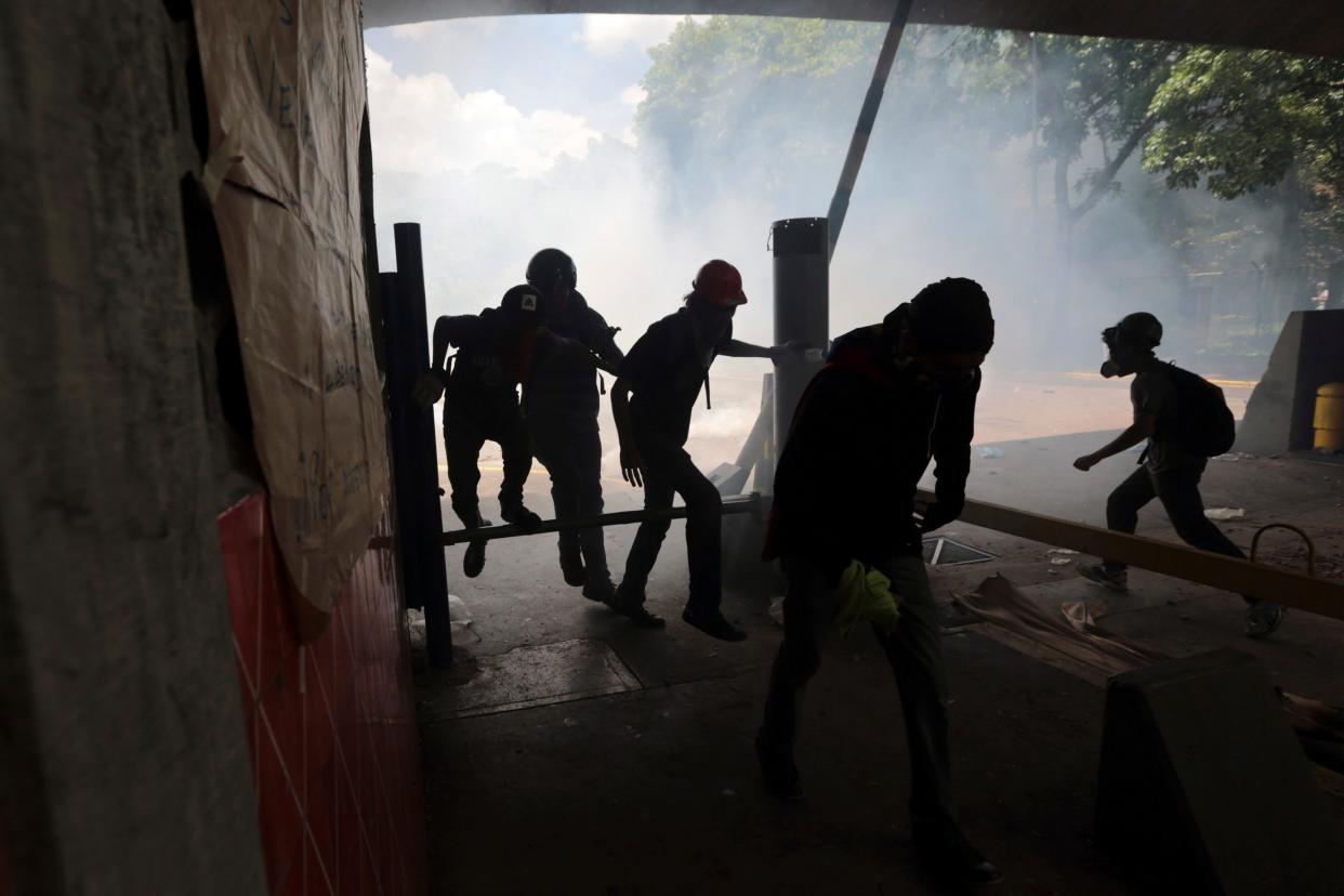 Students run from tear gas fired by National Police outside the Central University of Venezuela in Caracas,  - Copyright 2017 The Associated Press. All rights reserved.