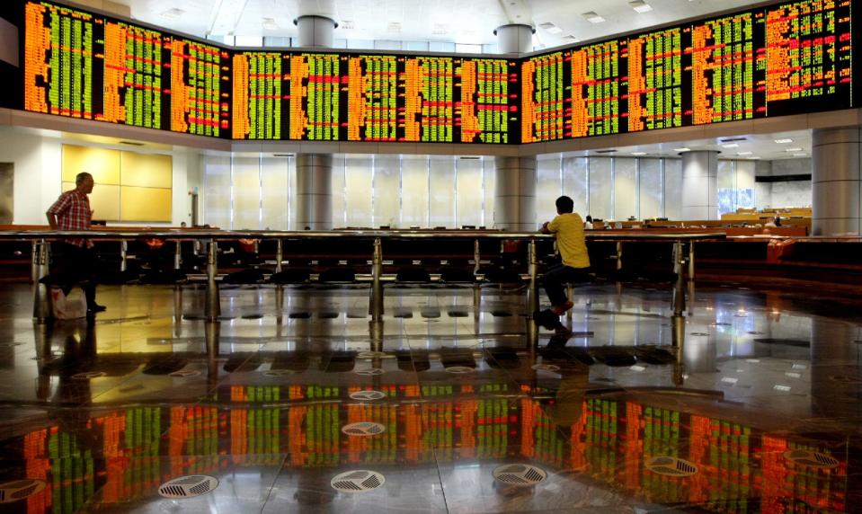 Investor studies share prices during the morning trading at a private stock market gallery in Kuala Lumpur, Malaysia, Tuesday, Feb. 4, 2014. Weakness in U.S. and Chinese manufacturing sent Asian stock markets sharply lower Tuesday. (AP Photo/Daniel Chan)