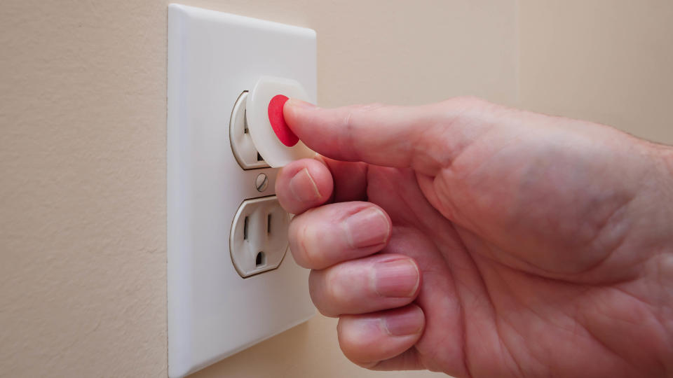 An outlet cover being placed in a power outlet