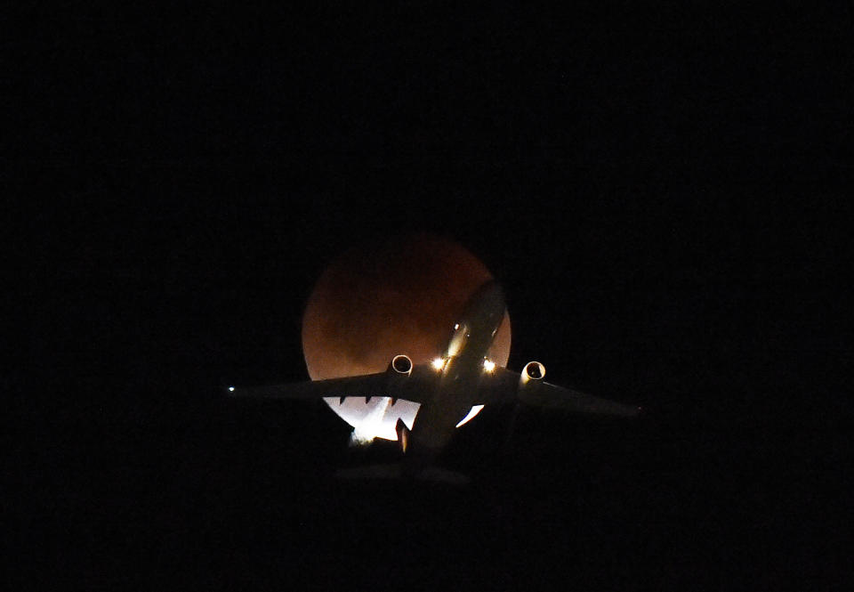 A plane flies passing the moon over Los Angeles.&nbsp;