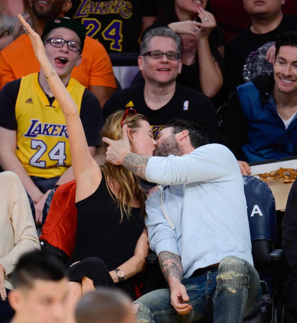Adam Levine (R) and Behati Prinsloo kiss at a basketball game between the Denver Nuggets and the Los Angeles Lakers at Staples Center on November 23, 2014 in Los Angeles, California