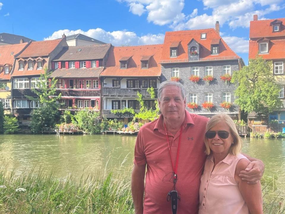 Ed Parry and his wife stood in front of houses and a river in Bamberg