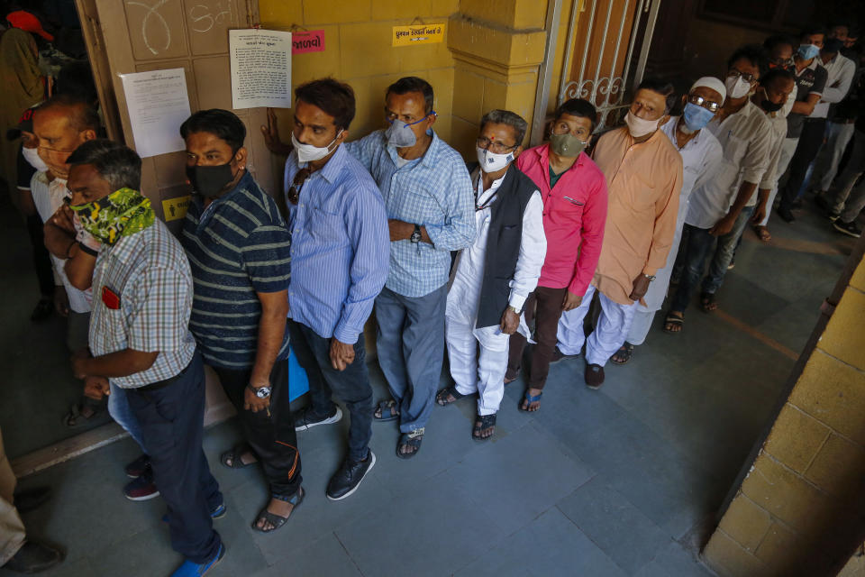 Indians wearing face masks as precaution against COVID-19, stand in queue to cast their vote for local body elections in Ahmedabad, India, Sunday, Feb. 21, 2021. (AP Photo/Ajit Solanki)