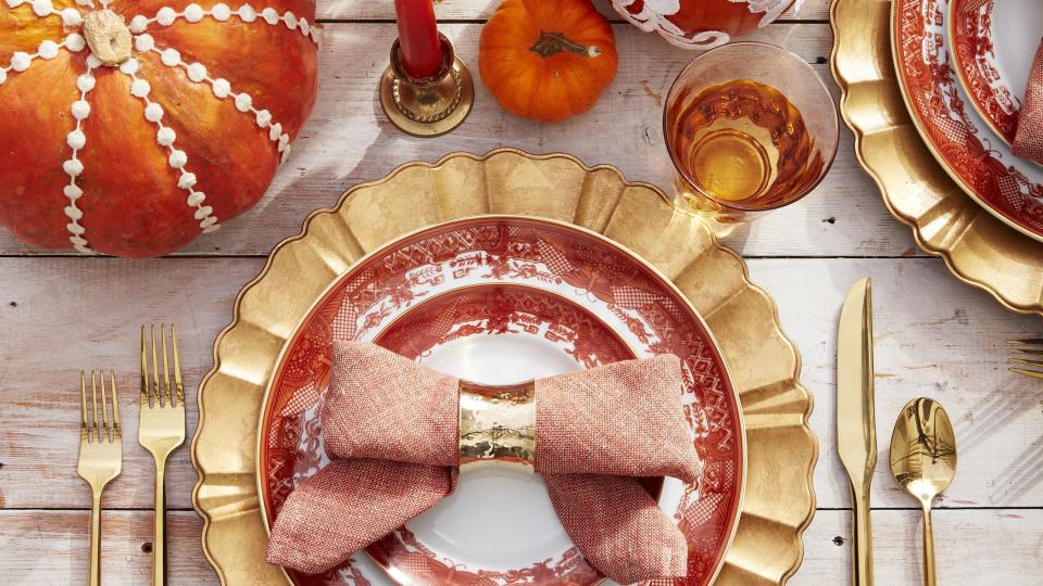 bowtie napkins on orange transferware plates with gold charger and flatware