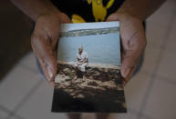 FILE - In this July 12, 2020, file photo, Reginalda Oliveira Costa, shows a photo of her mother, Nally Oliveira da Costa, or "Aunt Uia," in Rasa quilombo in Buzios, Brazil. Oliveira, who died from symptoms of coronavirus, worked for years as a maid in the beach resort of Armacao dos Buzios. She also stood up for her neighbors in Rasa, a poor community filled with the descendants of escaped slaves, becoming their voice in a fight for land rights. (AP Photo/Silvia Izquierdo, File)