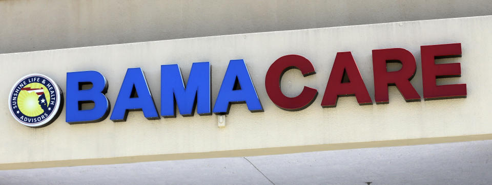 File- This May 11, 2017, file photo shows an Obamacare sign being displayed on the storefront of an insurance agency in Hialeah, Fla. A conservative federal judge in Texas on Friday, Dec. 14, 2018, ruled the Affordable Care Act “invalid” on the eve of the sign-up deadline for next year. But with appeals certain, even the Trump White House said the law will remain in place for now. In a 55-page opinion, U.S. District Judge Reed O’Connor ruled Friday that last year’s tax cut bill knocked the constitutional foundation from under “Obamacare” by eliminating a penalty for not having coverage. The rest of the law cannot be separated from that provision and is therefore invalid, he wrote. (AP Photo/Alan Diaz, File)