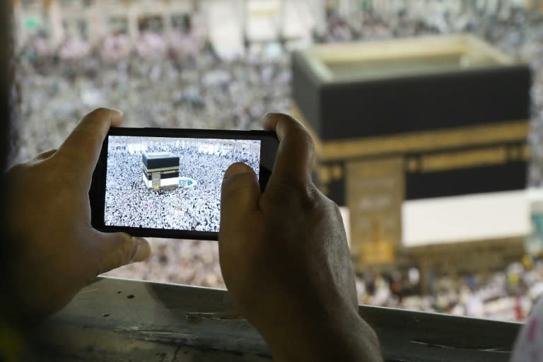 A man takes a picture of Muslim worshippers performing prayers around the Kaaba, Islam's holiest shrine, at the Grand Mosque in Saudi Arabia's holy city of Mecca on August 15, 2018