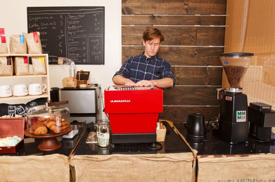 A man stands at an espresso machine.