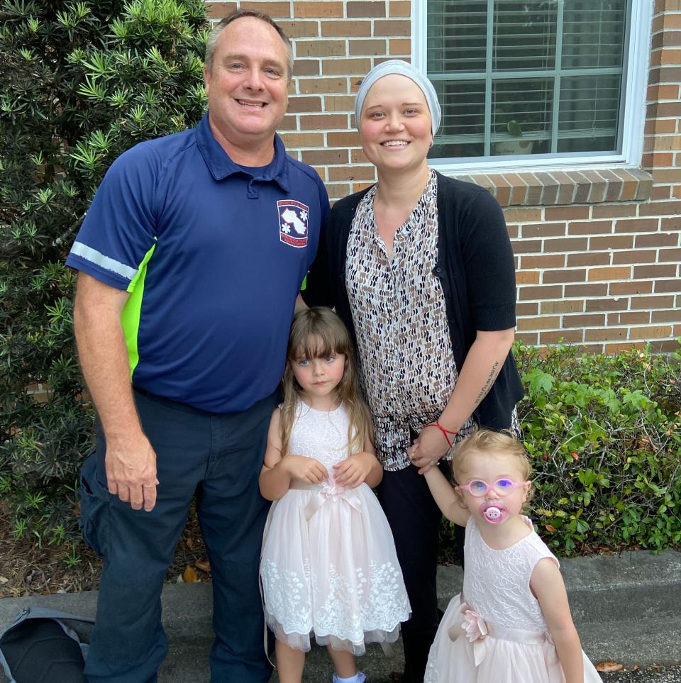 Casey Ward stands with her husband and two girls in front of their home.