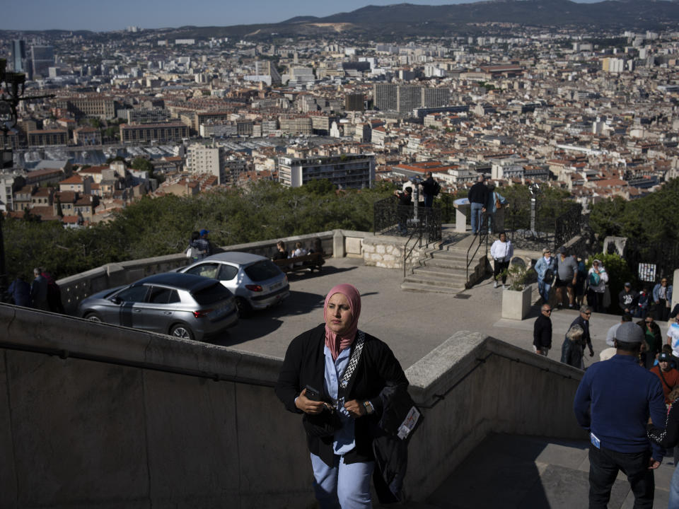 A woman climbs the stairs of the Notre Dame de la Garde Basilica in Marseille, southern France, Friday, April 19, 2024. (AP Photo/Daniel Cole)