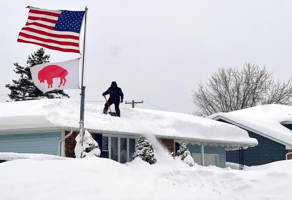A man in West Seneca clears snow from his roof.