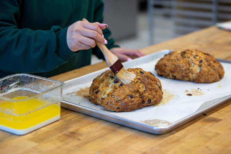 Pastry chef Terri Yee of Matawan brushes clarified butter onto freshly baked loaves of Irish soda bread at Baker's Grove in Shrewsbury.