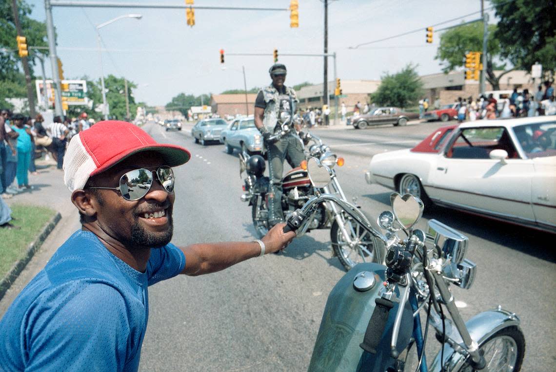 Dwight “Cowboy” Edmon pulls his motorcycle out of the 1985 Juneteenth parade in Fort Worth to watch. Riding in the background behind Edmon is John “Weed Hopper” Smith, vice president of the United Bikers.