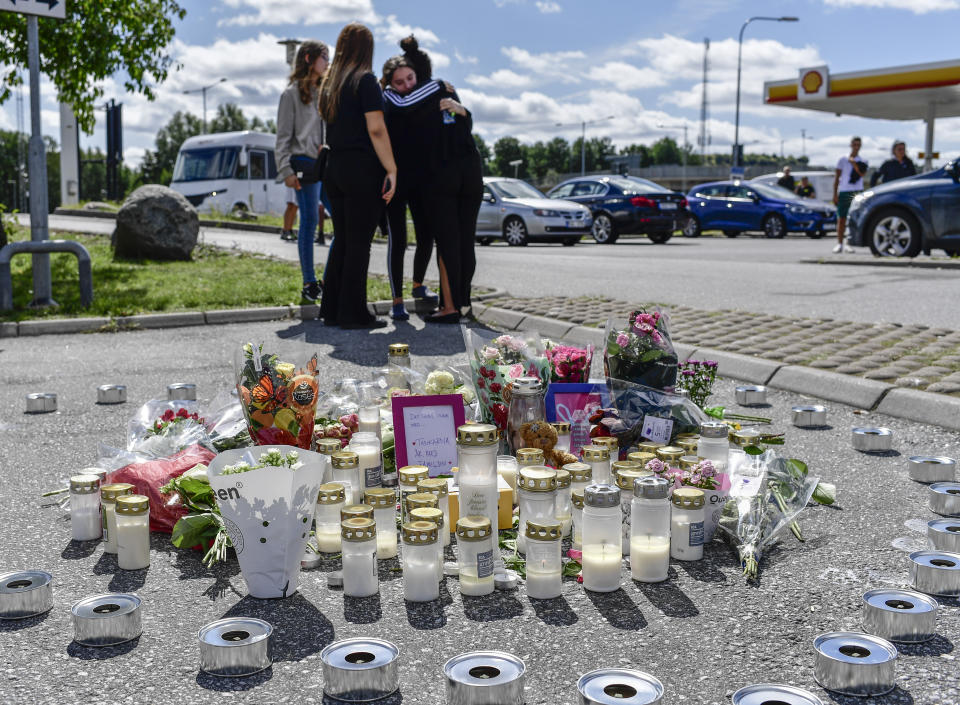 People gather near to where a twelve-year-old girl was shot and killed near a petrol station in Botkyrka, south of Stockholm, Sweden, Monday Aug. 3, 2020. (Stina Stjernkvist/TT via AP)