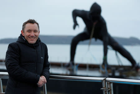 The sculptor Joseph Hillier poses for a photograph near his latest artwork, "Messenger", Britain's largest bronze sculpture, as it arrives by barge in Plymouth Sound before being transported to the Theatre Royal in Plymouth, Britain March 18, 2019. REUTERS/Peter Nicholls