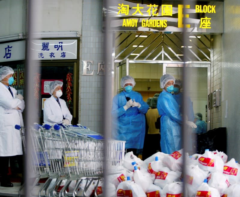 FILE PHOTO: Health workers in full surgical gear deliver household goods to the quarantined residents of Block E at Amoy Gardens housing estate in Hong Kong