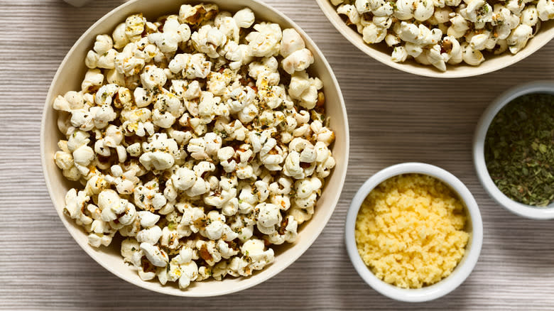 Popcorn in bowl with minced garlic and herbs on side