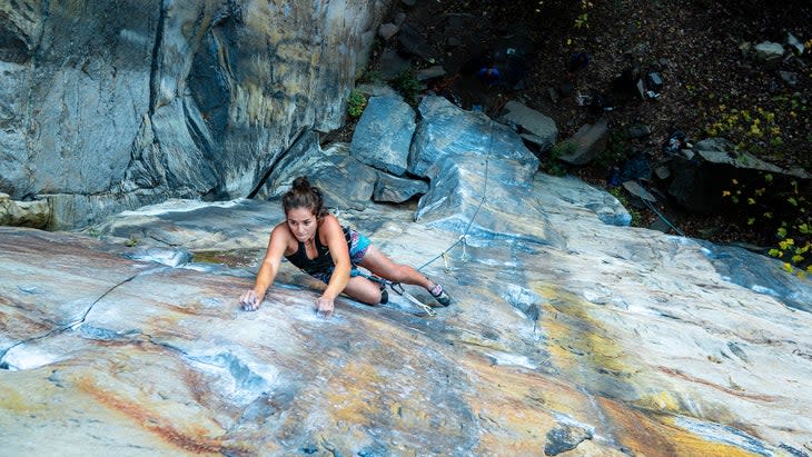 A top-down shot of a woman climbing up a slightly overhanging sport cliff in West Virginia