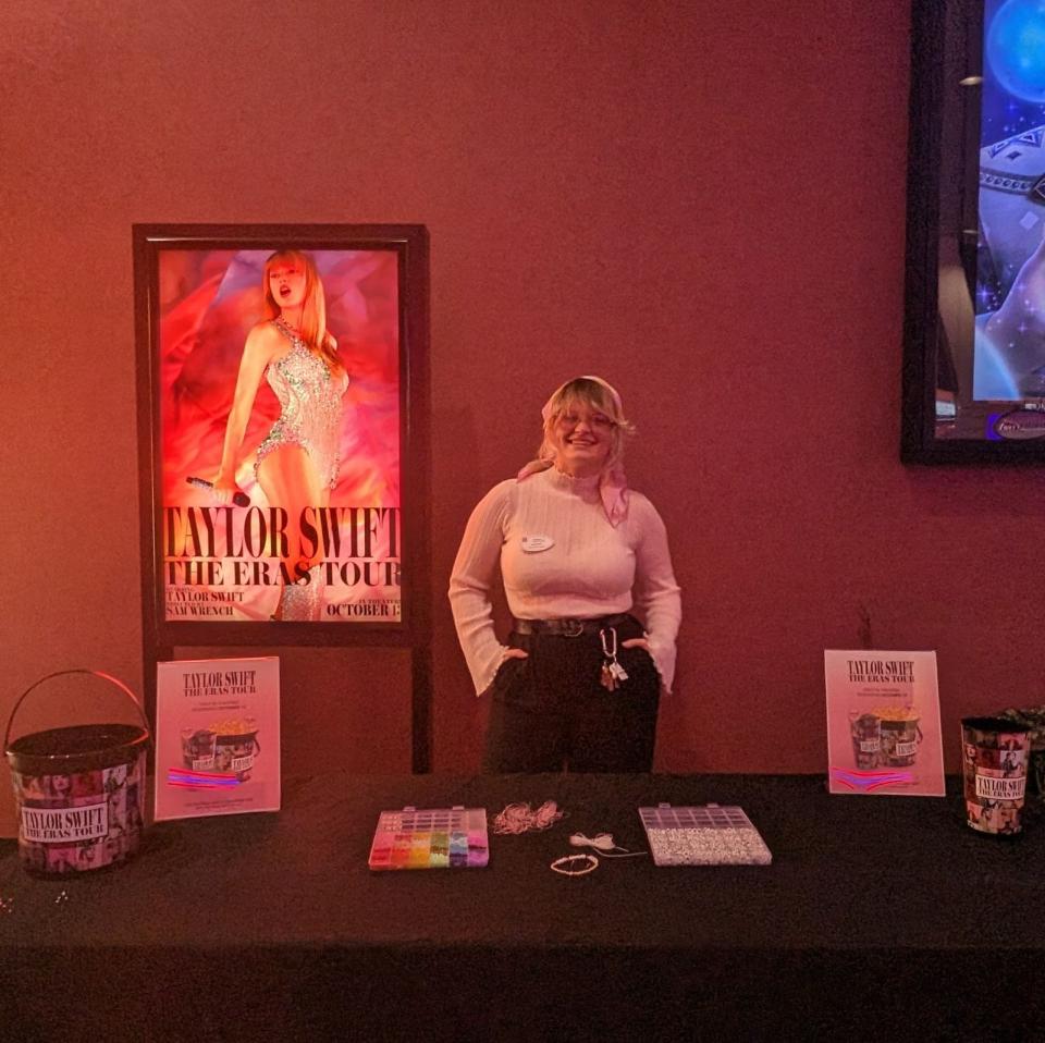 Marcus Theatres associate Kaitlyn Tucker shows off some items moviegoers can purchase (while supplies last) or win at screenings of the "Taylor Swift: The Eras Tour" concert film at the Crosswoods and Pickerington cinemas.