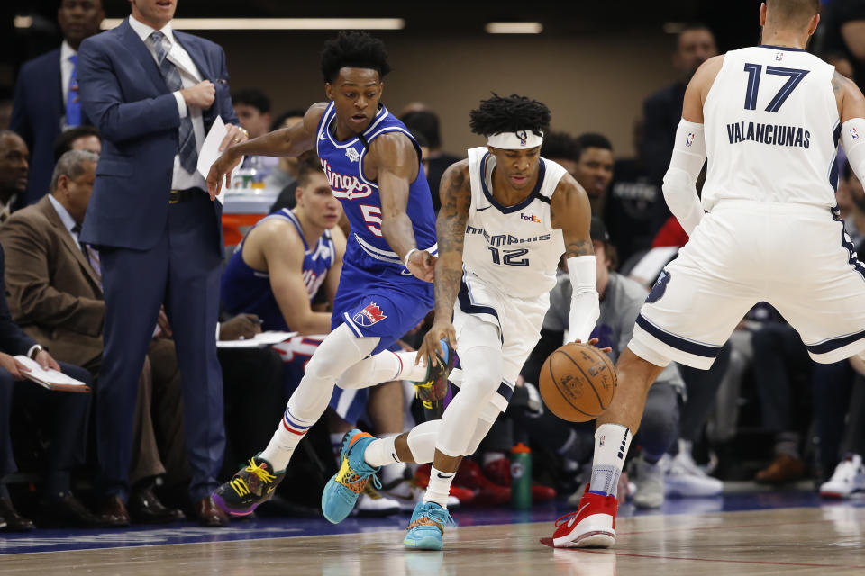 Memphis Grizzlies guard Ja Morant, right, dribbles aways from Sacramento Kings guard De'Aaron Fox, left, during the first quarter of an NBA basketball game in Sacramento, Calif., Thursday, Feb. 20, 2020. (AP Photo/Rich Pedroncelli)