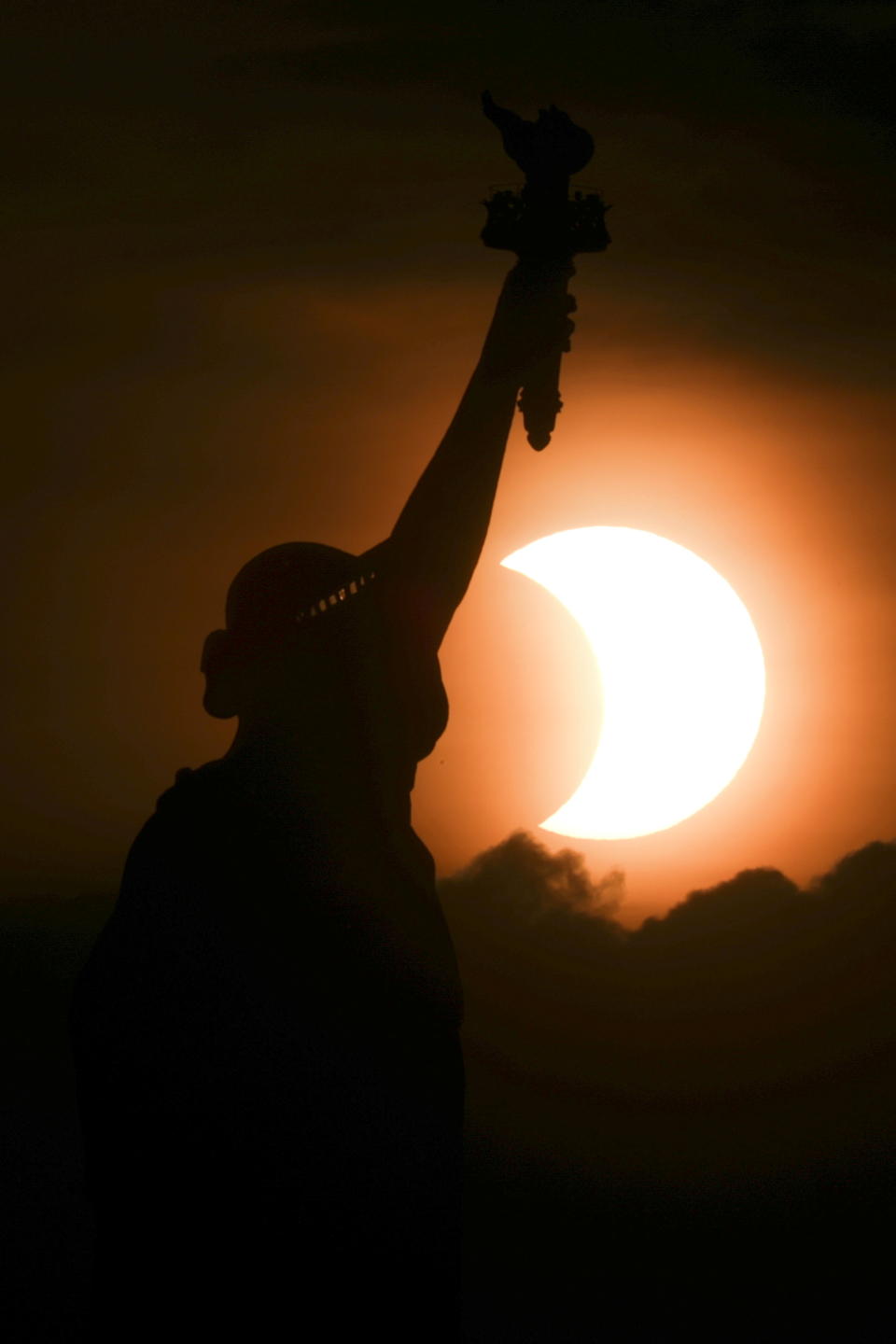 The partially eclipsed sun rises behind the Statue of Liberty in New York City, New York, U.S., early on June 10, 2021. REUTERS/Bjoern Kils/New York Media Boat     TPX IMAGES OF THE DAY