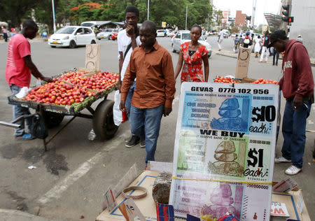 Locals walk past old currency notes on display along a street in the capital Harare, Zimbabwe, November 18, 2016. Picture taken November 18, 2016. REUTERS/Philimon Bulawayo